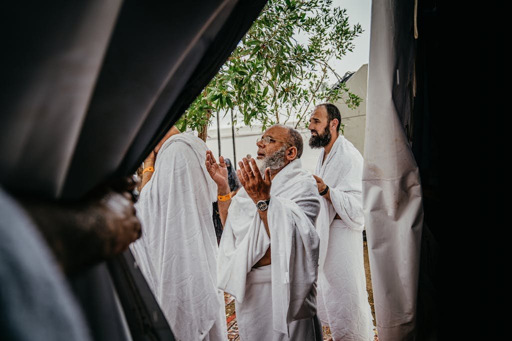 A group of men in white robes participate in a spiritual prayer outdoors, embracing cultural and religious traditions.