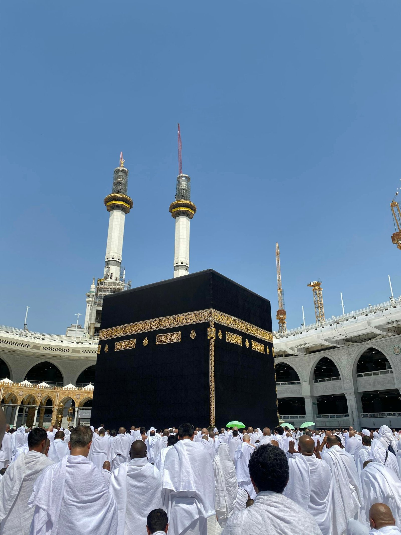 Pilgrims in white garments gather around the Kaaba in Mecca for Hajj rituals.