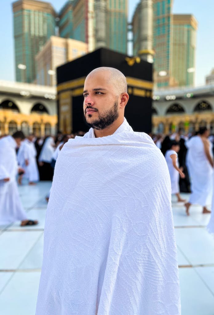 A man in traditional white robe participates in Hajj at the Kaaba, Mecca, Saudi Arabia.