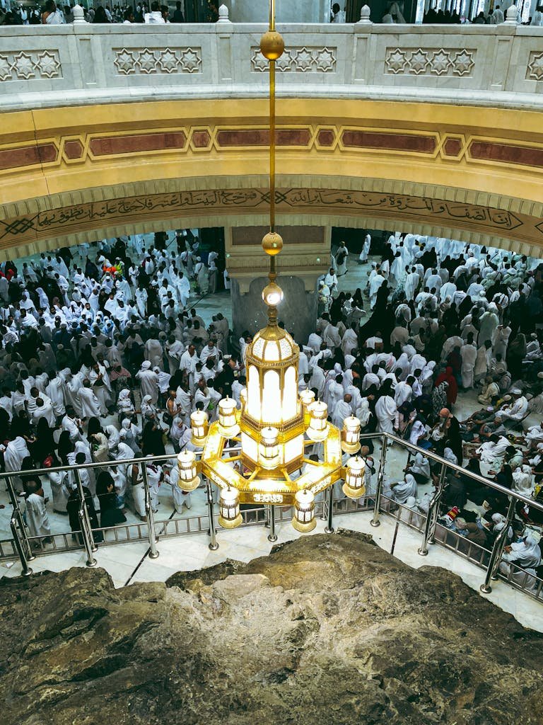 Interior view of Al-Masjid Al-Haram in Mecca with crowds gathered and decorative architecture.